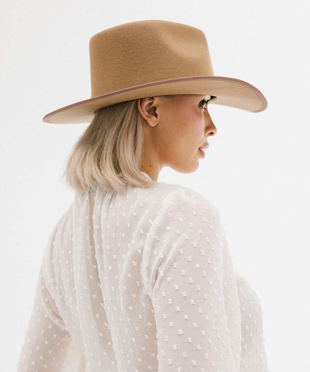 Person wearing a brown felt western hat and a white top, facing sideways against a white background #color_brown