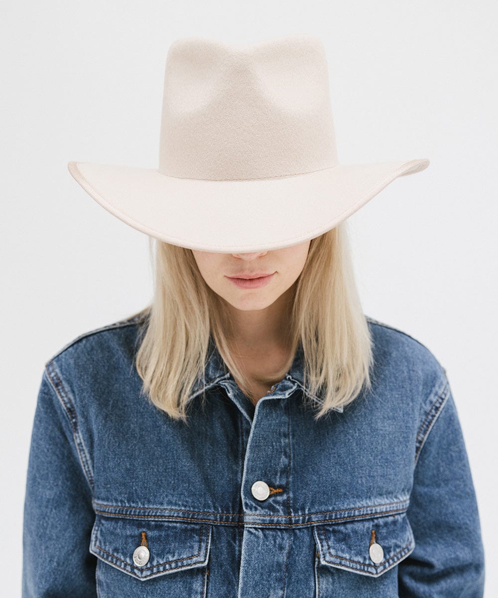 Woman wearing a cream felt western hat and a denim shirt against a white background #color_cream