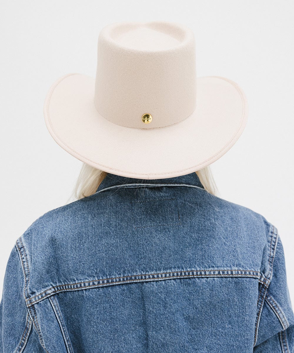 Person wearing a cream felt western hat and a denim shirt, facing behind against a white background #color_cream