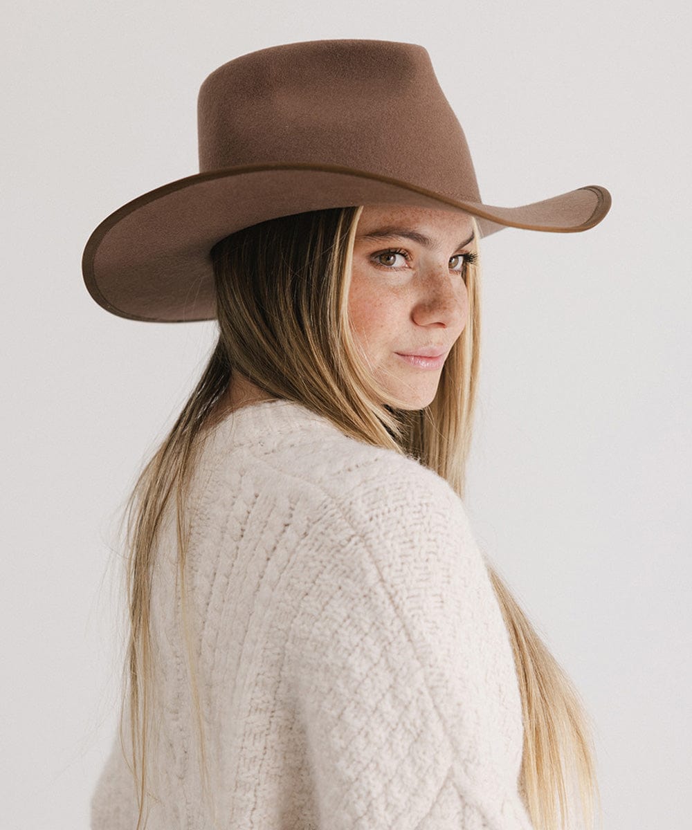 Woman wearing a chocolate colored felt western hat and a cream sweatshirt, looking sideways against a white background #color_chocolate