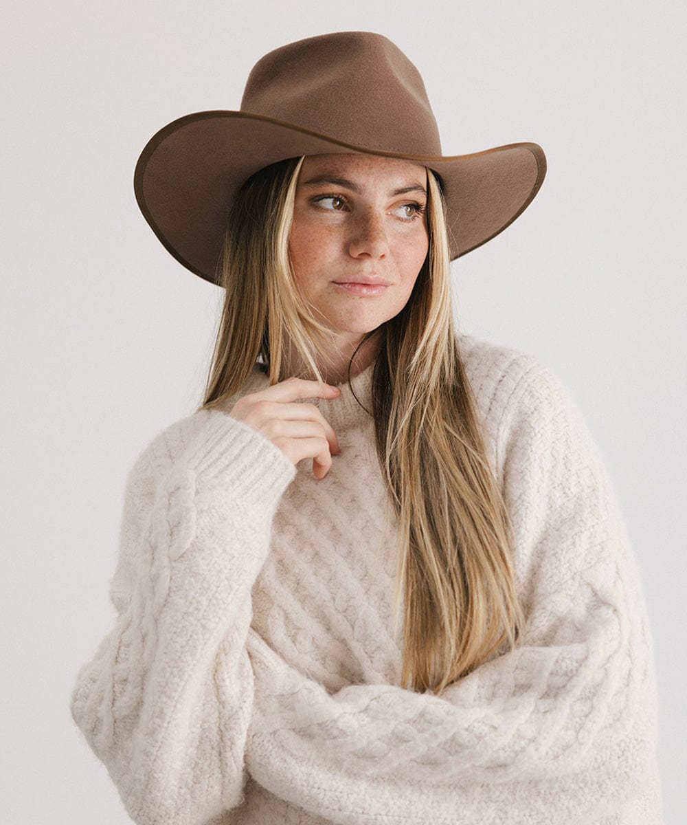 Woman with long hair wearing a chocolate colored felt western hat and a cream sweatshirt, posing against a white background #color_chocolate