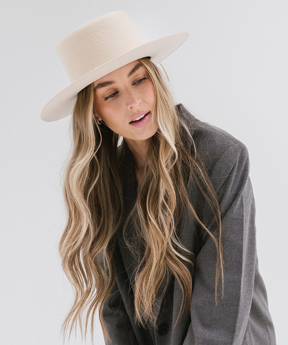 Woman with long hair wearing a cream Maise classic flat brim hat with a hat band and a grey blazer against a plain background #color_cream