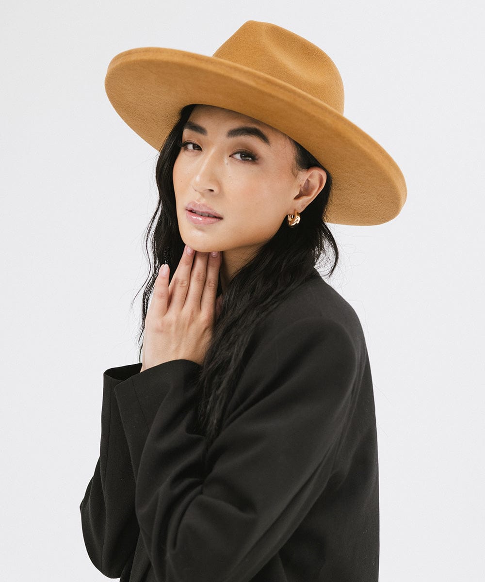 Woman wearing a cinnamon colored  pencil brim felt fedora hat and a black blazer, posing against a white background #color_cinnamon