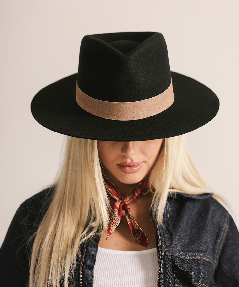 Woman wearing a black fedora hat with a brown band against a white background #color_black-brown
