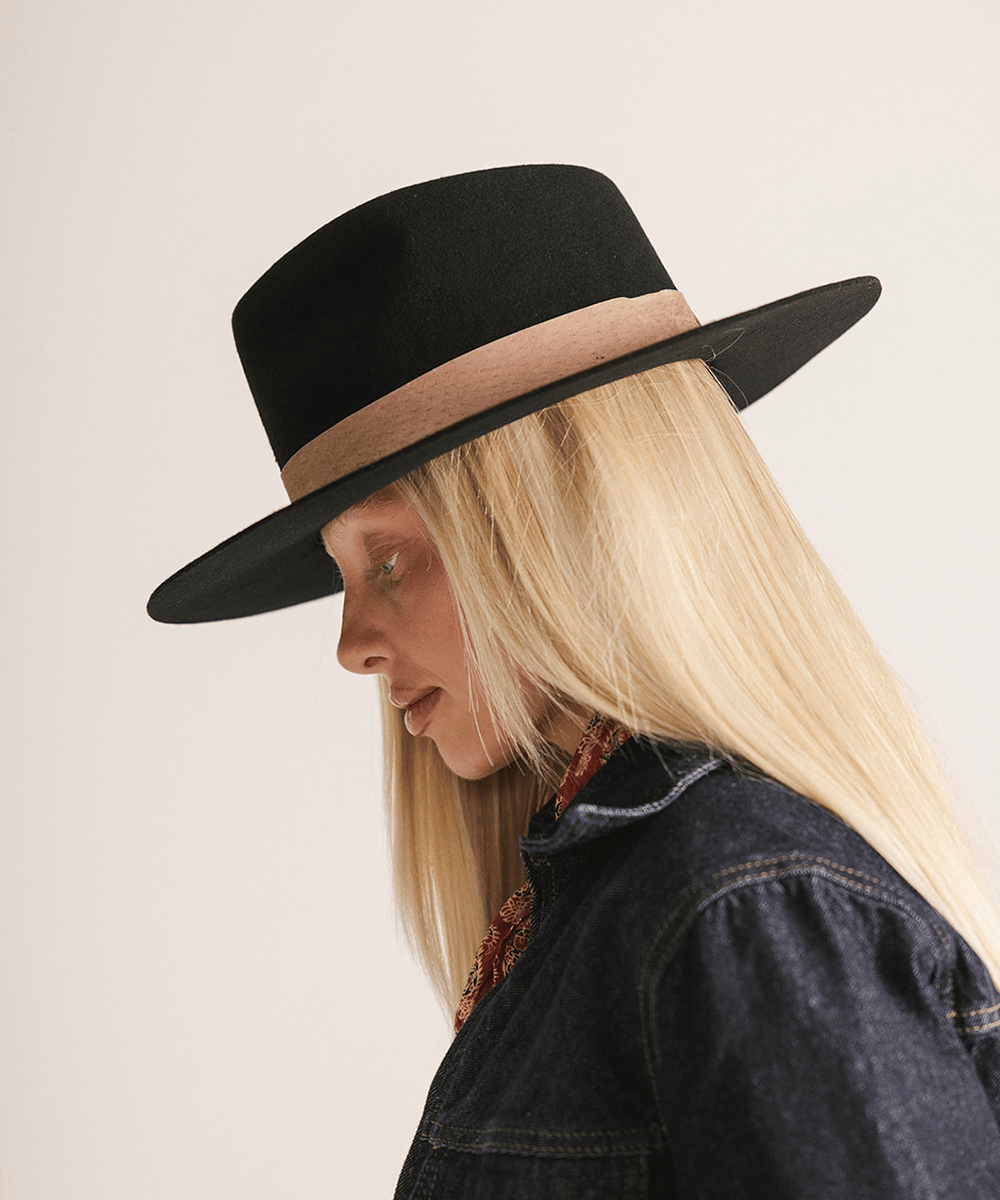 Woman wearing a black fedora hat with a brown band against a white background #color_black-brown