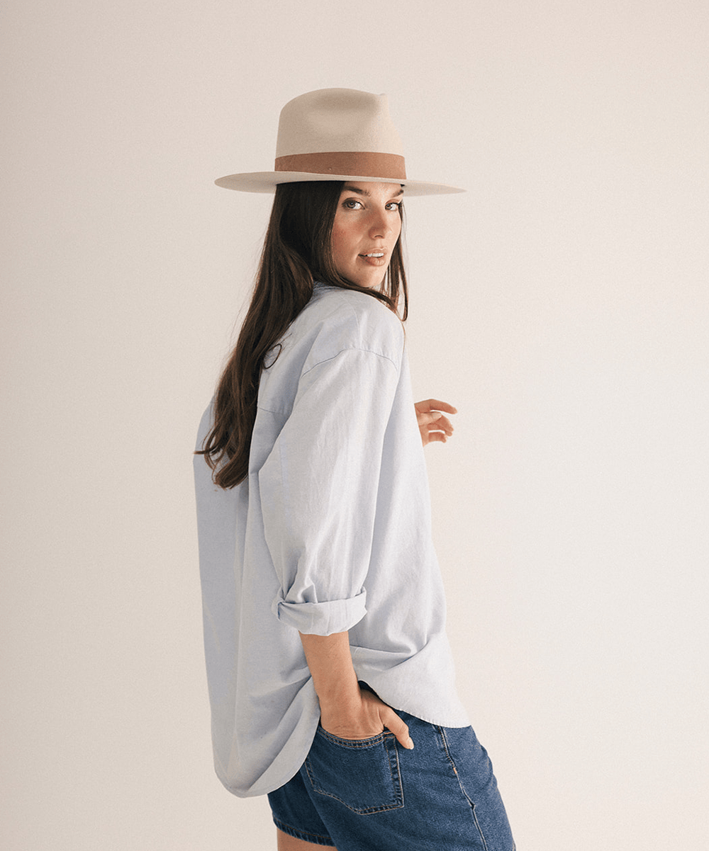 Woman wearing a fedora hat with a brown band on a white background #color_ivory