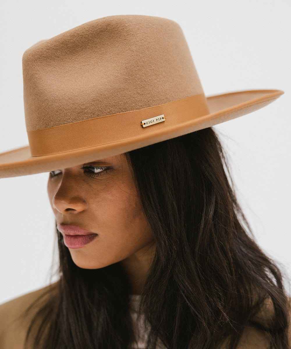 Woman wearing a brown hat with a band looking sideways against a plain background #color_brown