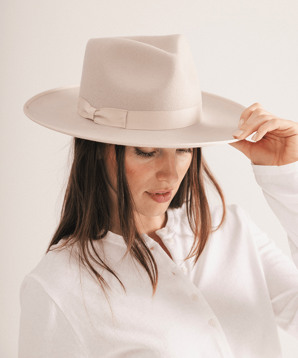 Woman wearing a fedora hat with a band on a white background #color_ivory