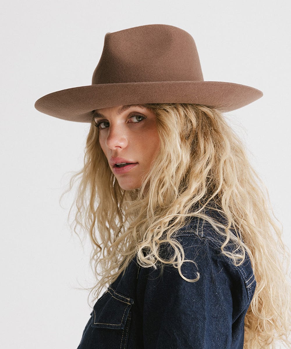 Woman with blonde hair wearing a chocolate colored Rowan Wide Brim Fedora Hat and a denim shirt against a plain background #color_chocolate