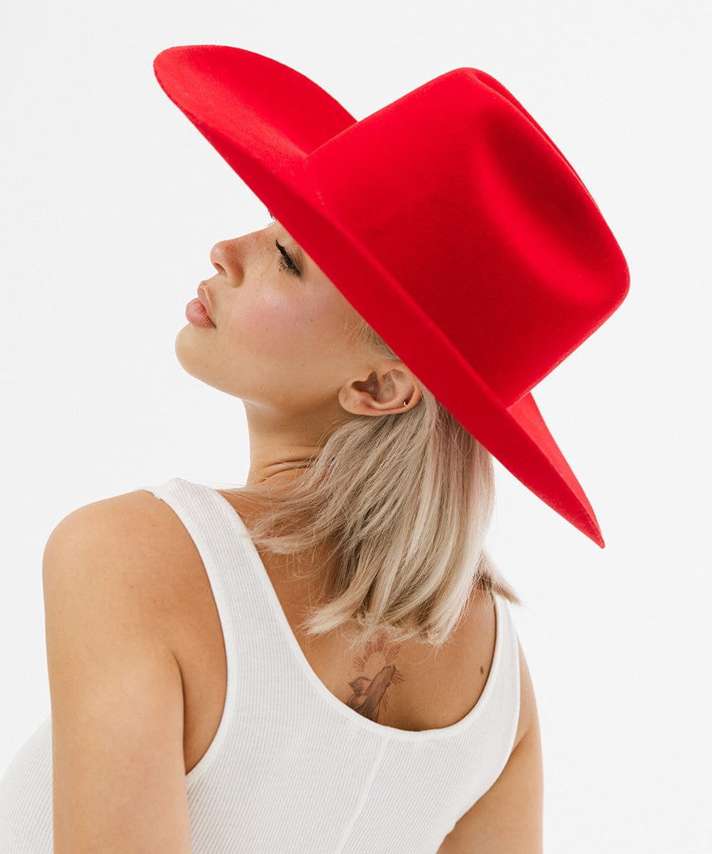 Woman wearing a cherry red cowboy hat and a white top, facing sideways against a plain background #color_cherry red