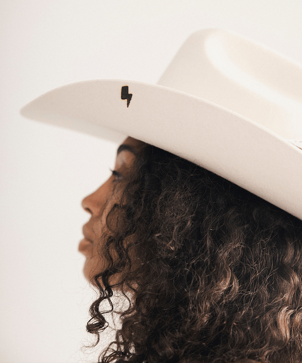 Woman wearing a white cowboy hat with a lightning brand on a plain background #color_off white