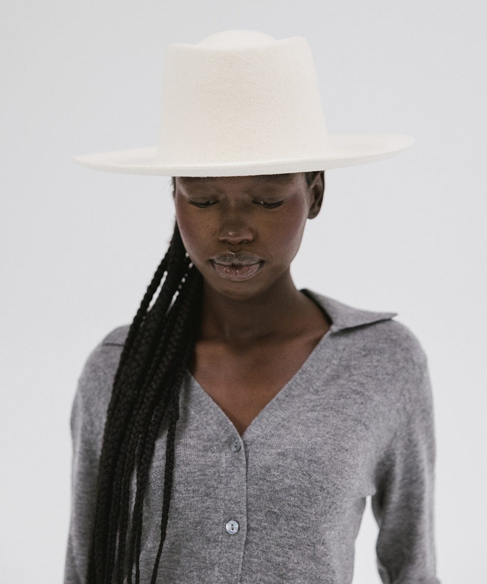 Woman wearing an off white gambler hat and a grey shirt against a plain background #color_off white