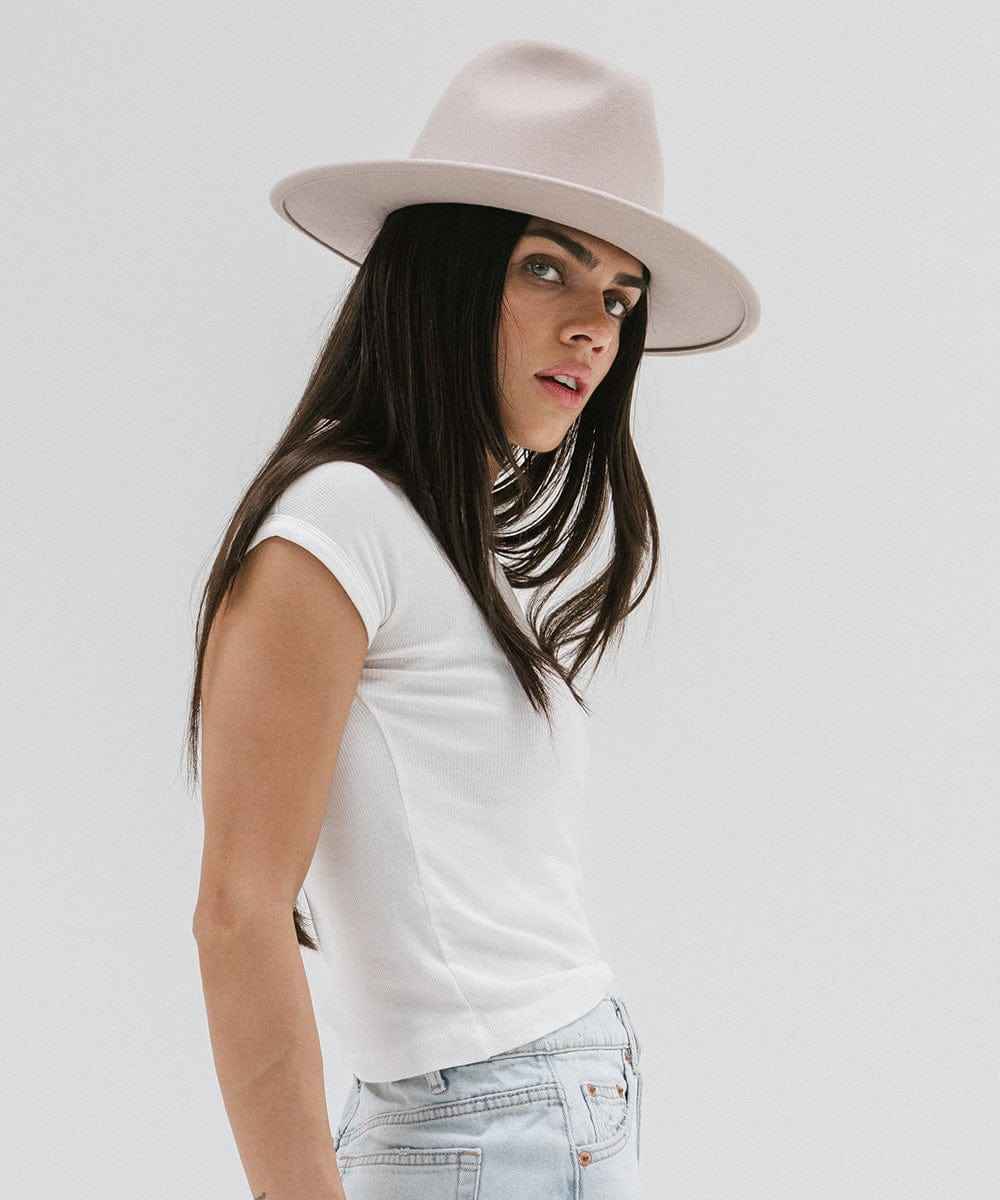 Woman wearing an ivory colored fedora hat and white t-shirt on a plain background #color_ivory
