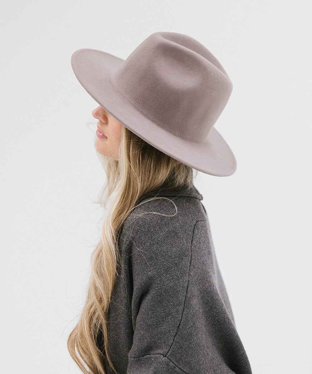 Woman wearing a light grey fedora hat and a dark grey jacket, facing sideways against a plain background #color_light grey