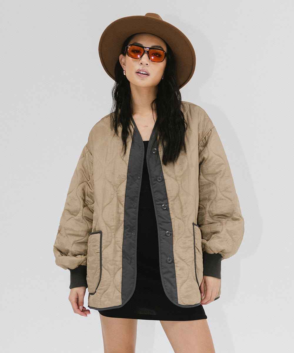 Woman wearing a brown fedora hat, sunglasses, and a beige jacket against a plain background #color_brown