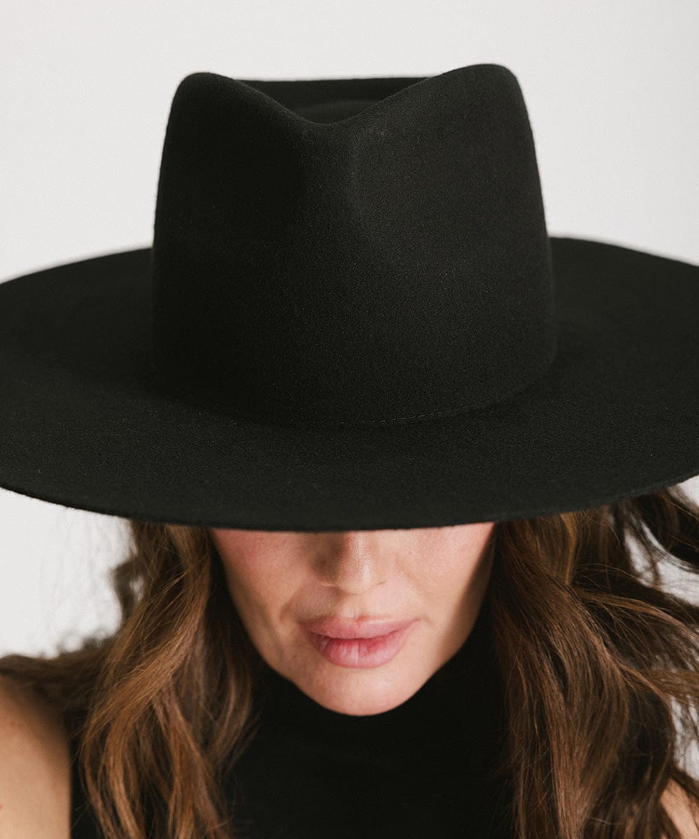 Woman wearing a black fedora hat against a plain background #color_black