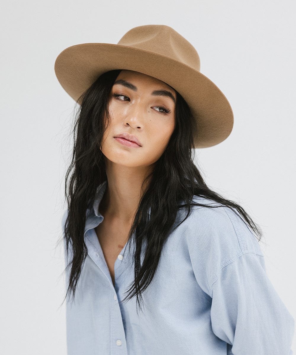 Woman wearing a brown fedora hat and a light blue shirt, posing against a white background #color_brown
