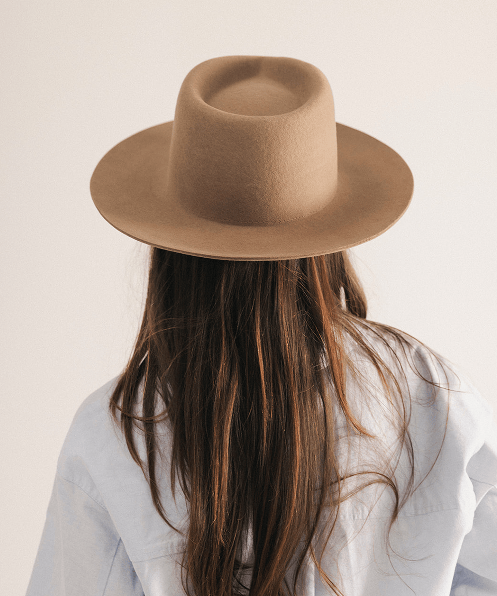 Woman wearing a brown fedora hat with a neutral background #color_brown