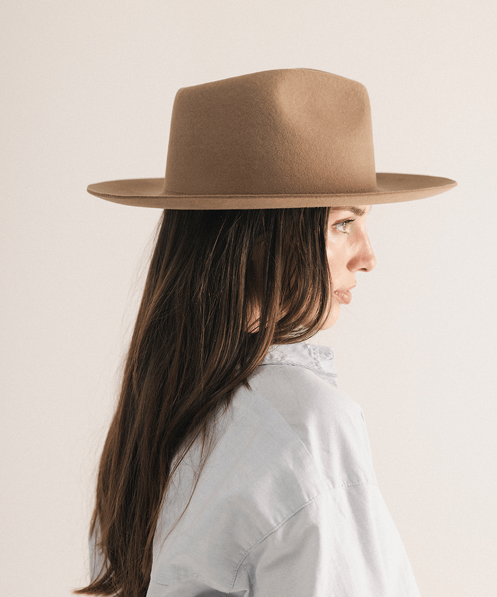 Woman wearing a brown fedora hat with a neutral background #color_brown