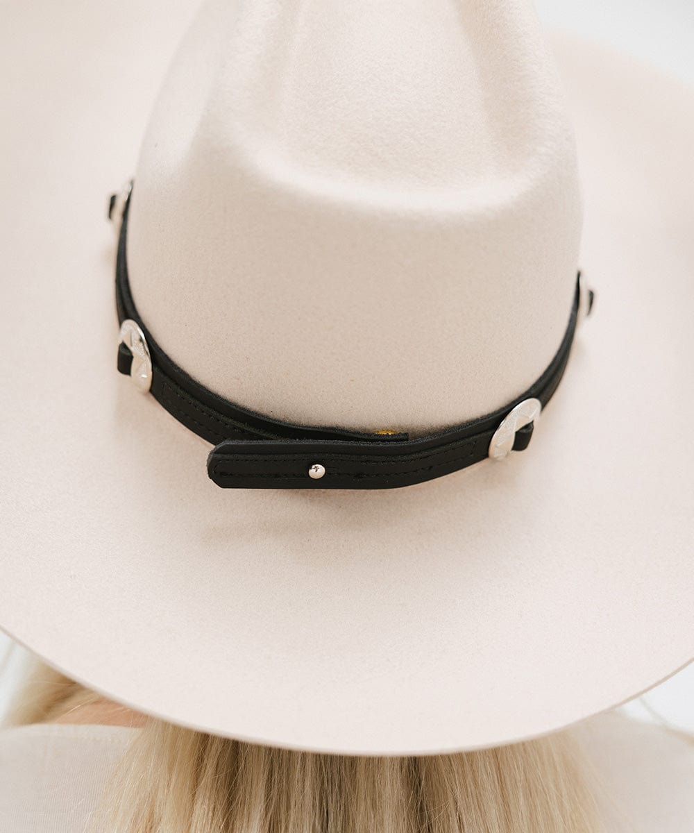 Close up image of a white hat with a black western style genuine leather hat band against a plain background #color_black