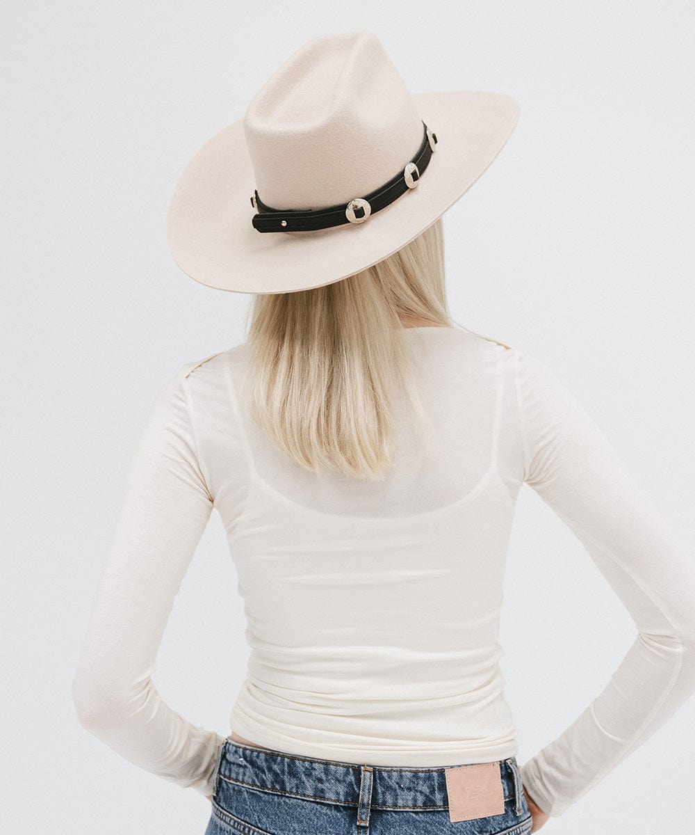 A woman wearing a white hat with a black western style genuine leather hat band and a white top against a plain background #color_black