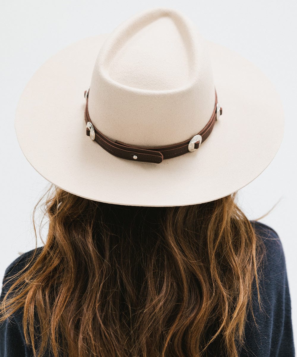 Woman wearing a white hat with a chocolate colored western style  genuine leather hat band and a blue sweater against a plain background #color_chocolate