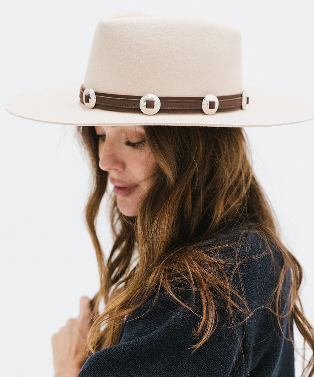 Woman wearing a white hat with a chocolate colored western style  genuine leather hat band and a blue sweater, posing sideways against a plain background #color_chocolate