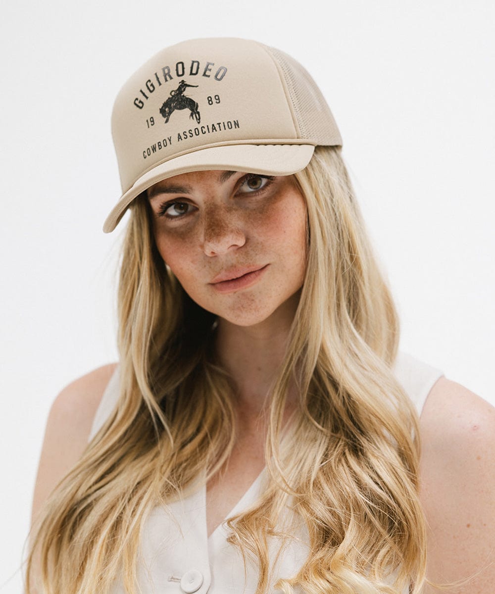 Woman wearing a tan cap with golden 'GIGIRODEO' text and logo against a plain background  #color_tan