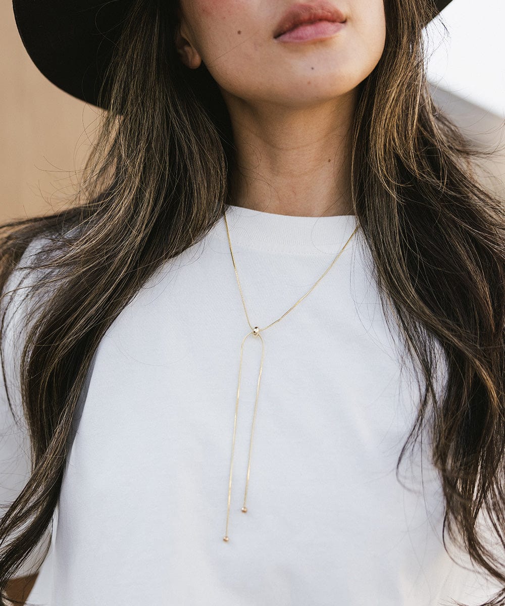Woman wearing a white t-shirt and a gold chain bolo band on her neck #color_gold