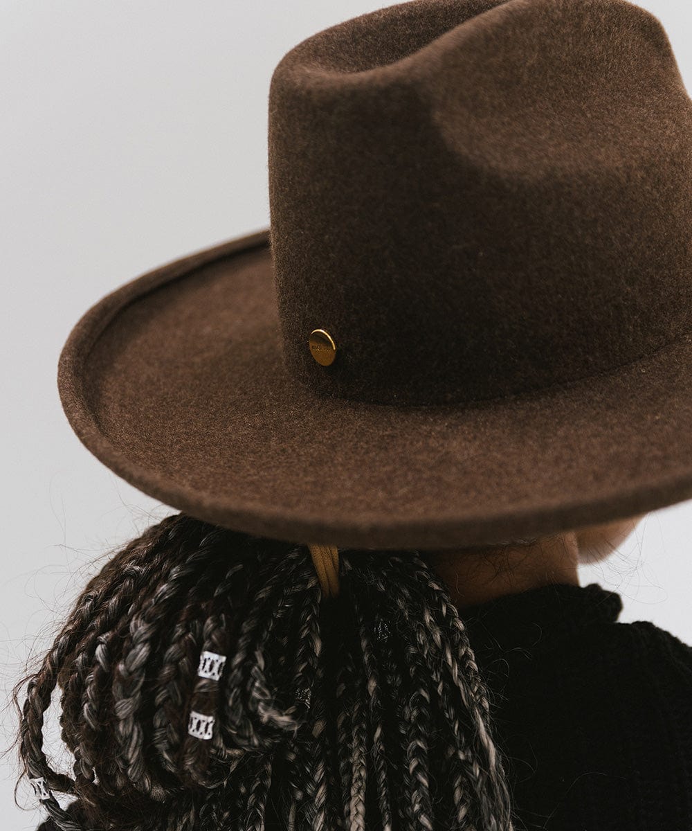 Person wearing a mix brown colored western hat with a pencil brim and a tall crown against a plain background  #color_mix brown