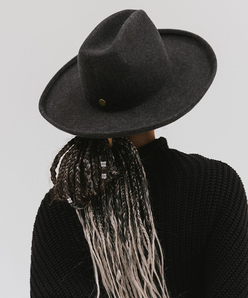 Person wearing a mix charcoal colored western hat with a pencil brim and a tall crown and a black sweater against a plain background  #color_mix charcoal