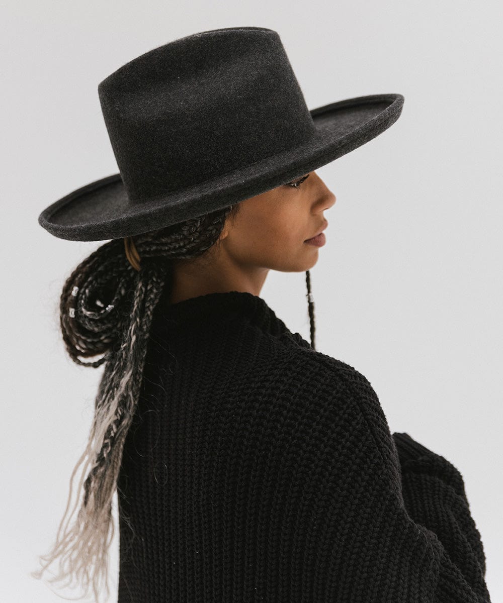 Woman wearing a mix charcoal colored western hat with a pencil brim and a tall crown and a black sweater, facing sideways against a plain background  #color_mix charcoal