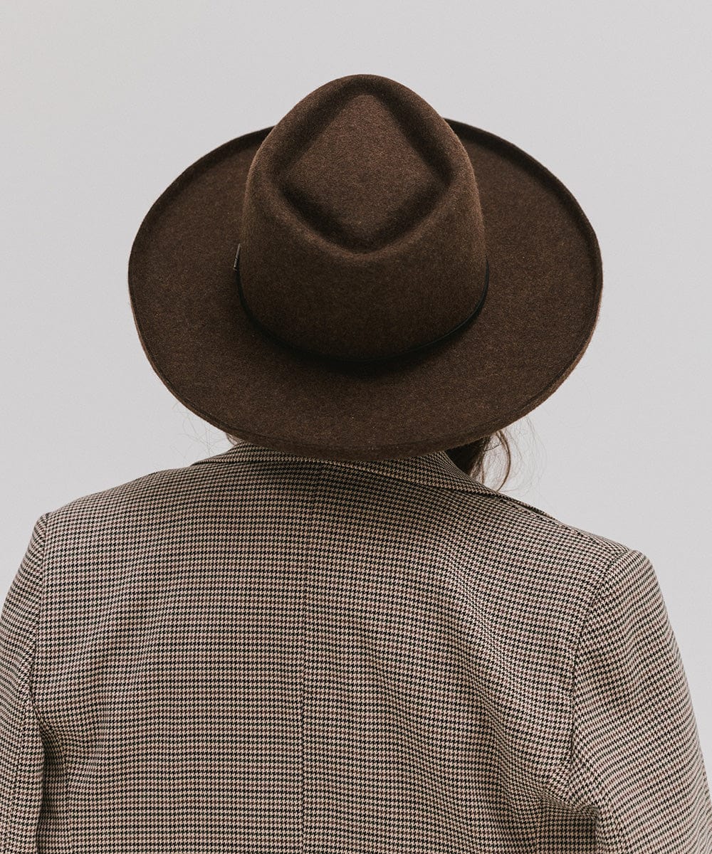 Person wearing a mix brown Lennon pencil brim fedora hat with a hat band and a coat against a plain background #color_mix brown
