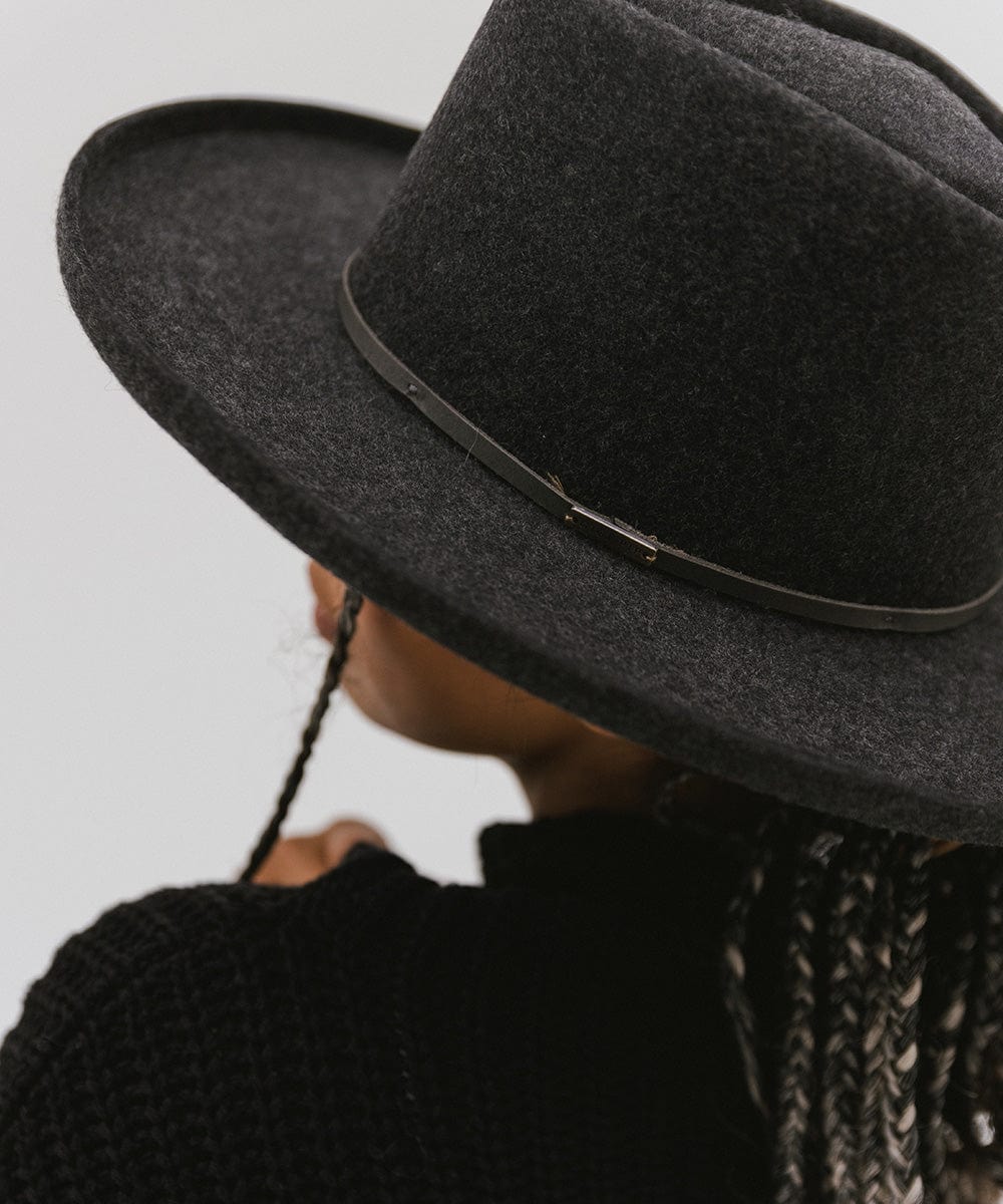 A close up image of a person wearing a mix charcoal colored Lennon Pencil Brim Fedora Hat with a hat band against a plain background  #color_mix charcoal