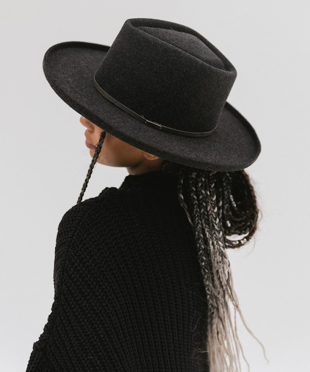 Woman wearing a mix charcoal colored Lennon pencil brim fedora hat with a hat band and a black sweater, facing sideways against a plain background #color_mix charcoal
