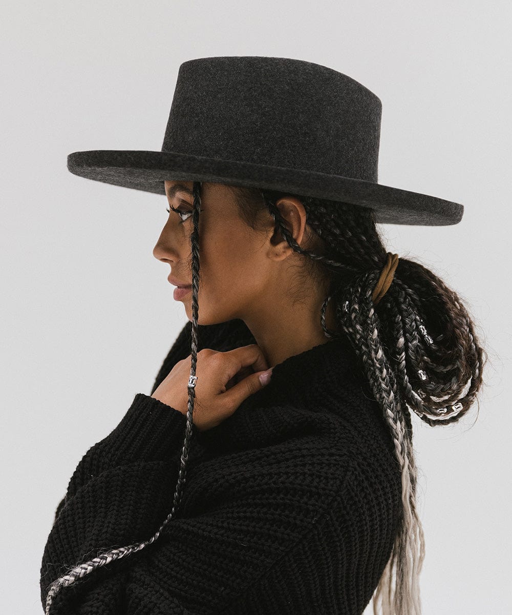 Woman wearing a mix charcoal colored Lennon pencil brim fedora hat with a hat band and a black sweater, posing sideways against a plain background #color_mix charcoal