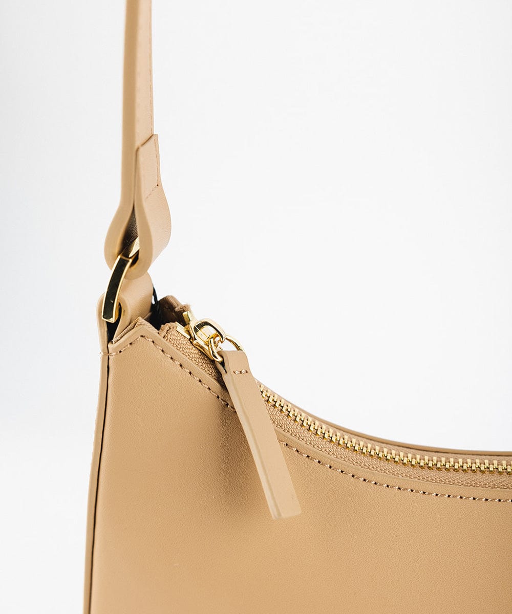 A tan genuine leather handbag with a golden zipper on a plain background  #color_tan