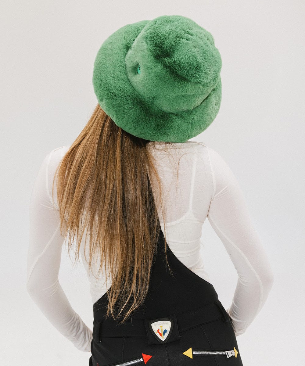 Person with long hair wearing a green faux fur bucket hat and a white top against a plain background #color_evergreen