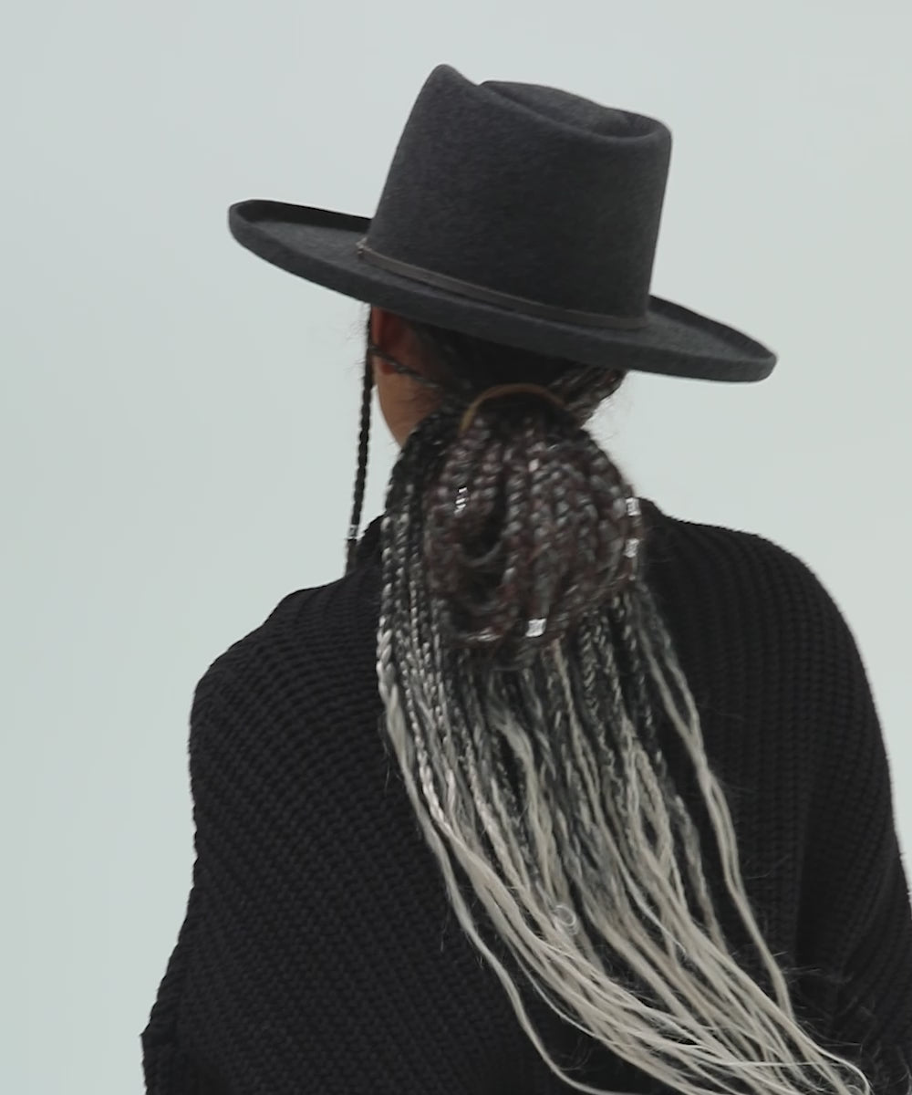 Woman wearing a mix charcoal colored Lennon pencil brim fedora hat with a hat band and a black sweater, posing against a plain background #color_mix charcoal