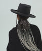 Woman wearing a mix charcoal colored Lennon pencil brim fedora hat with a hat band and a black sweater, posing against a plain background #color_mix charcoal