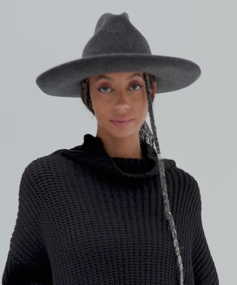 Woman wearing a mix charcoal colored western hat with a pencil brim and a tall crown and a black sweater against a plain background  #color_mix charcoal