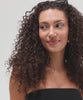 Woman with curly hair wearing black sunglasses and a black top, posing against a plain background #color_black