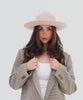 Woman wearing a cream fedora hat with a hat band and a white top with a checkered coat posing against a plain background #color_cream