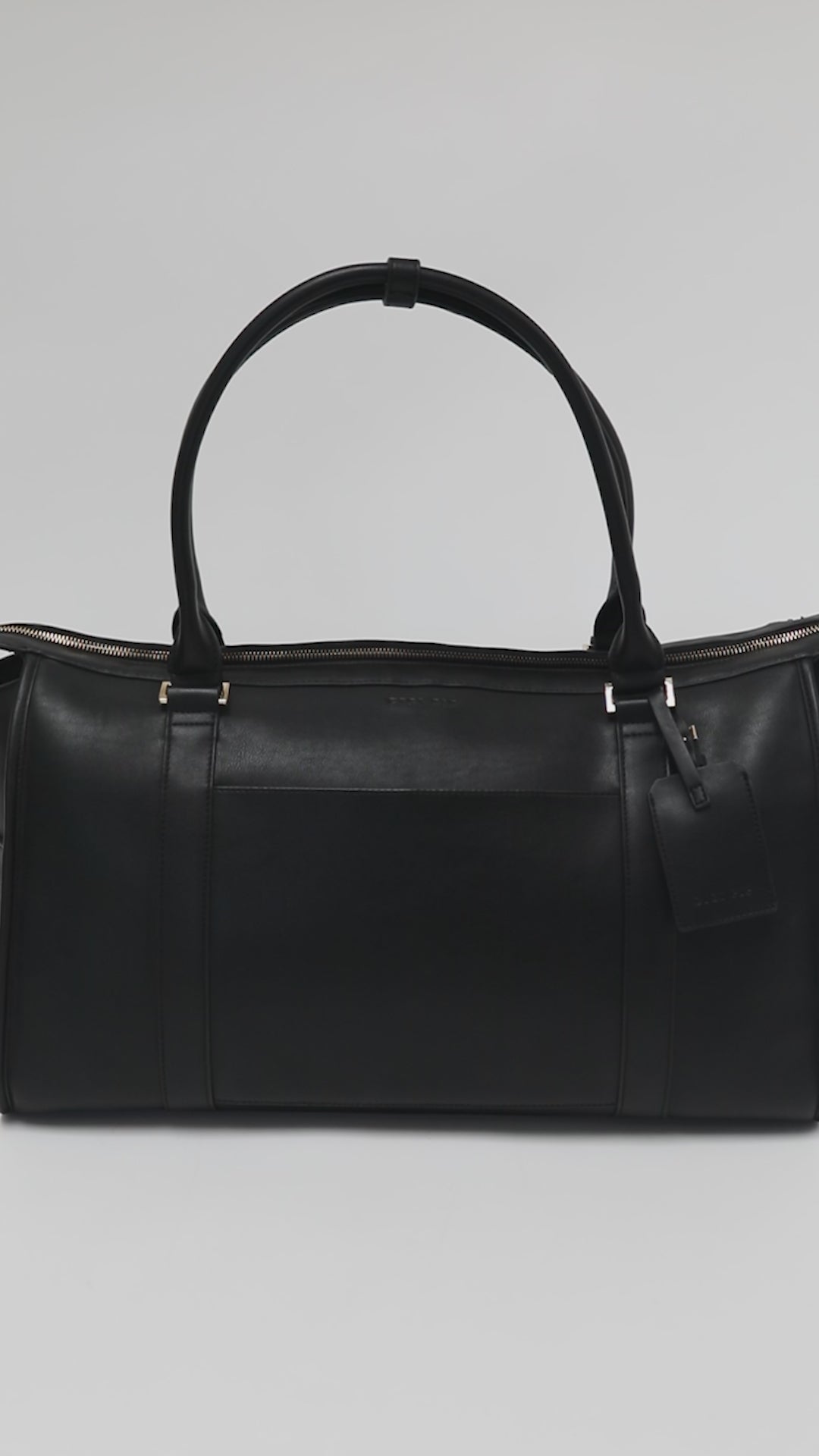 Person showing all the features of a black vegan leather weekender bag against a plain background #color_black