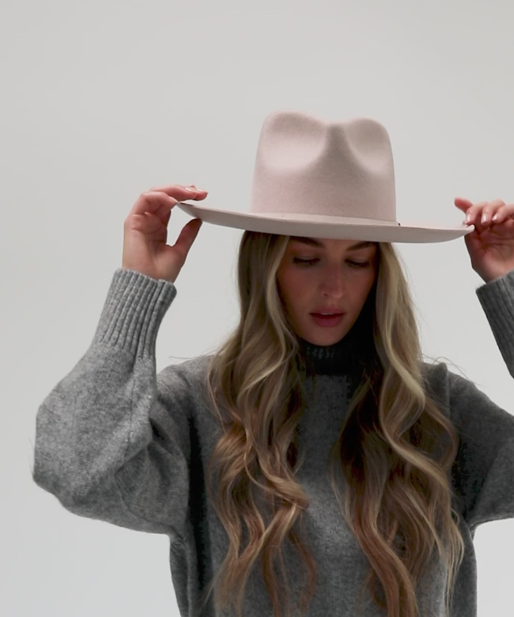 Woman with long hair wearing an ivory colored Rowan Wide Brim Fedora Hat and a grey sweatshirt against a plain background #color_ivory
