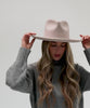 Woman with long hair wearing an ivory colored Rowan Wide Brim Fedora Hat and a grey sweatshirt against a plain background #color_ivory