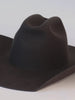 A dark brown cowboy hat being designed with bands, burning, horse pin and a feather #color_dark brown