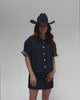 Woman wearing a vintage blue colored cowboy hat, a denim shirt and a denim skirt, posing against a plain background
#color_vintage blue