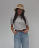 Woman wearing a beige crochet packable bucket hat, a grey t-shirt and blue jeans, posing against a plain background #color_natural stripe