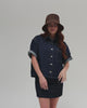 Woman wearing a chocolate colored hat, a denim shirt and denim skirt, posing against a plain background #color_chocolate